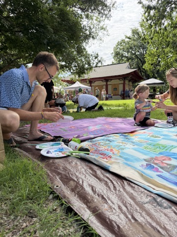 Community members painting Surface/Self canvases outdoors.