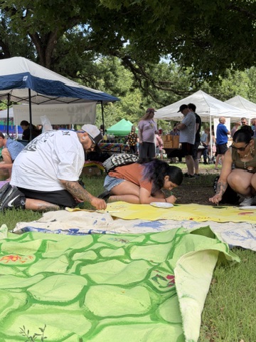 Participants painting a green Surface/Self canvas outdoors.