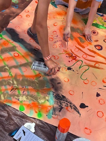 Hands spray-painting an orange Surface/Self canvas.
