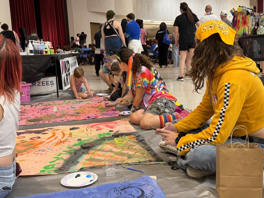 Pride attendees painting Surface/Self canvases indoors.