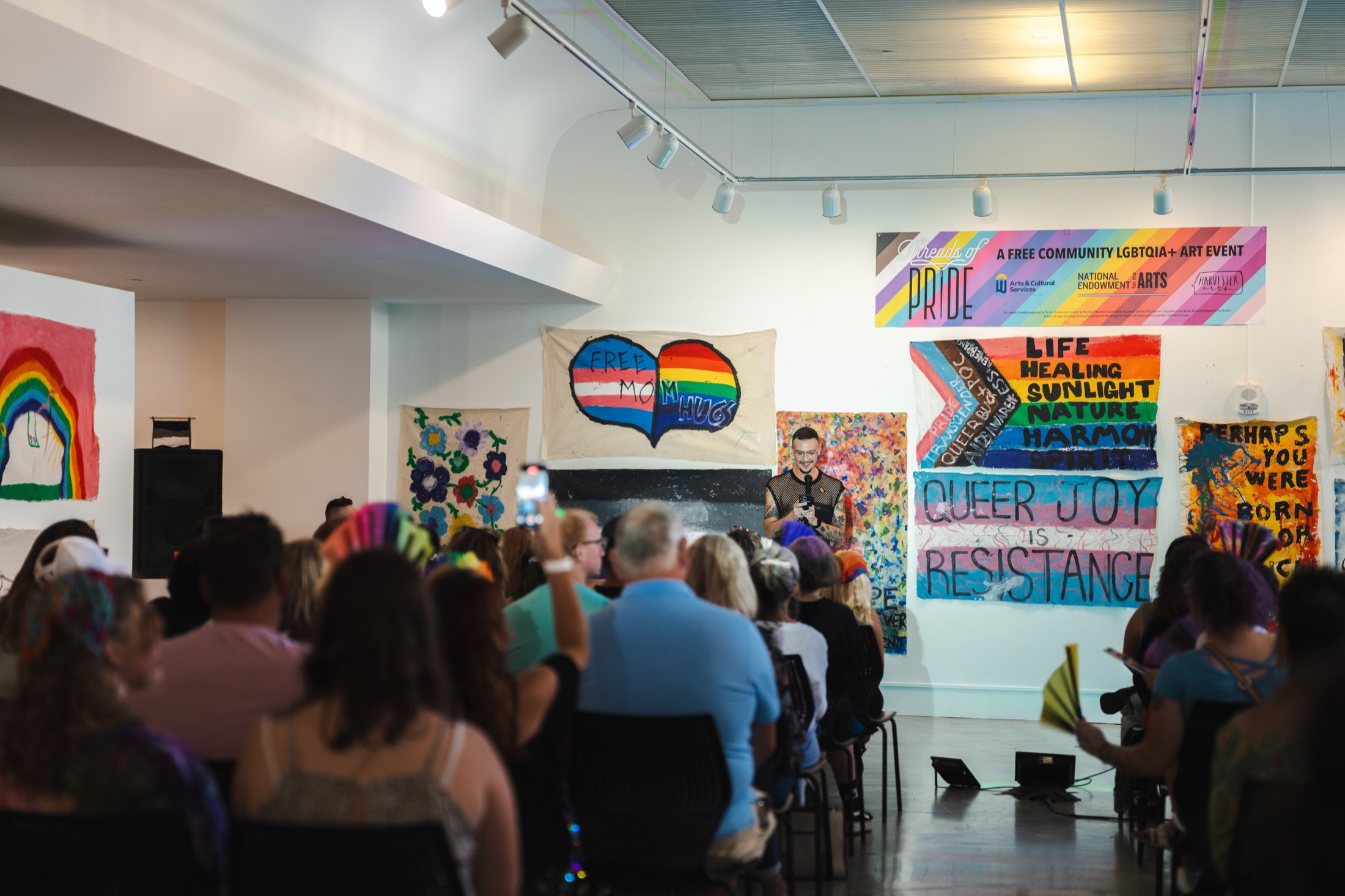 Threads of Pride gallery event with colorful community artwork.